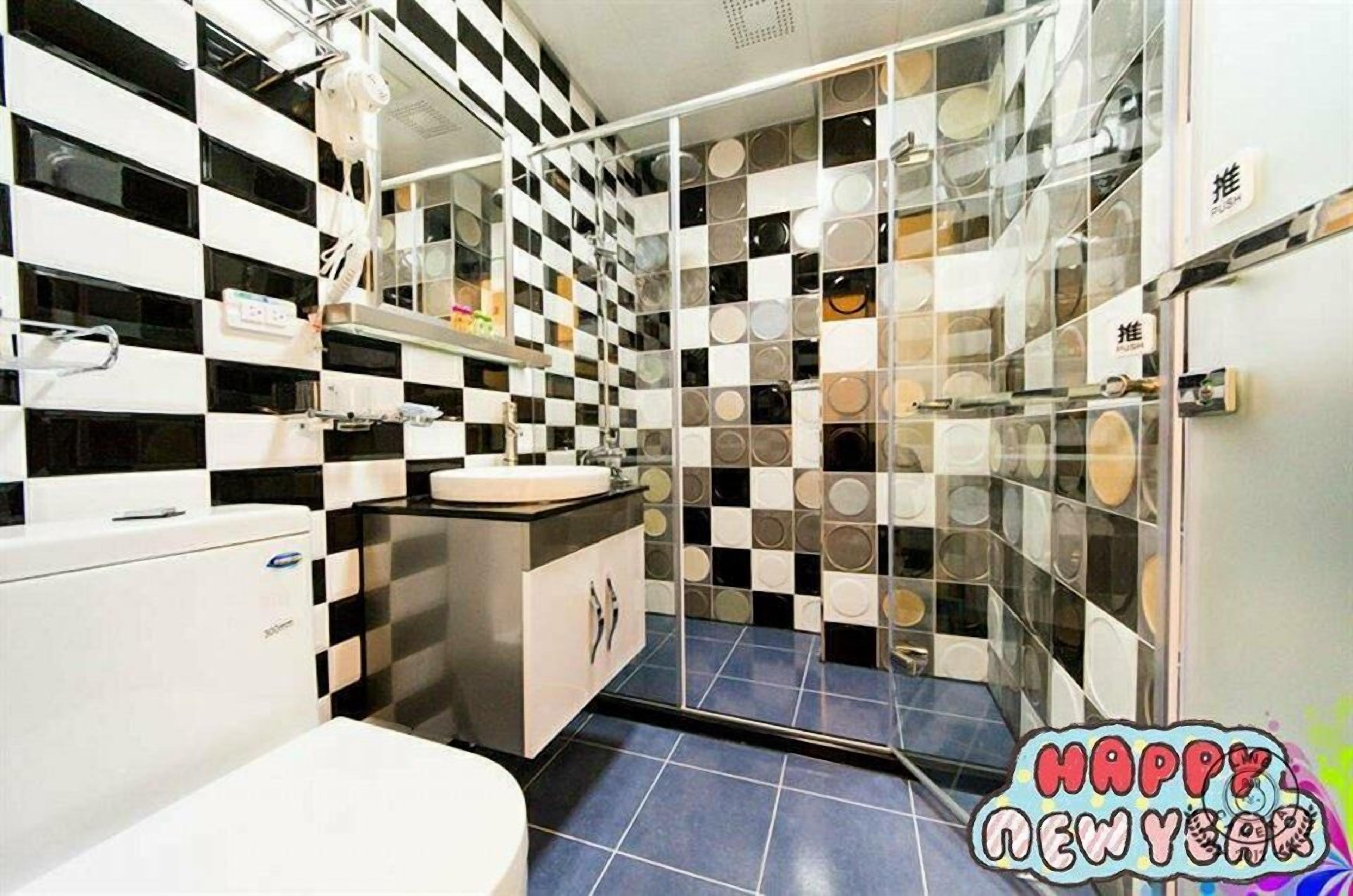 A modern bathroom with a checkered floor pattern, a sink, and a glass shower enclosure.