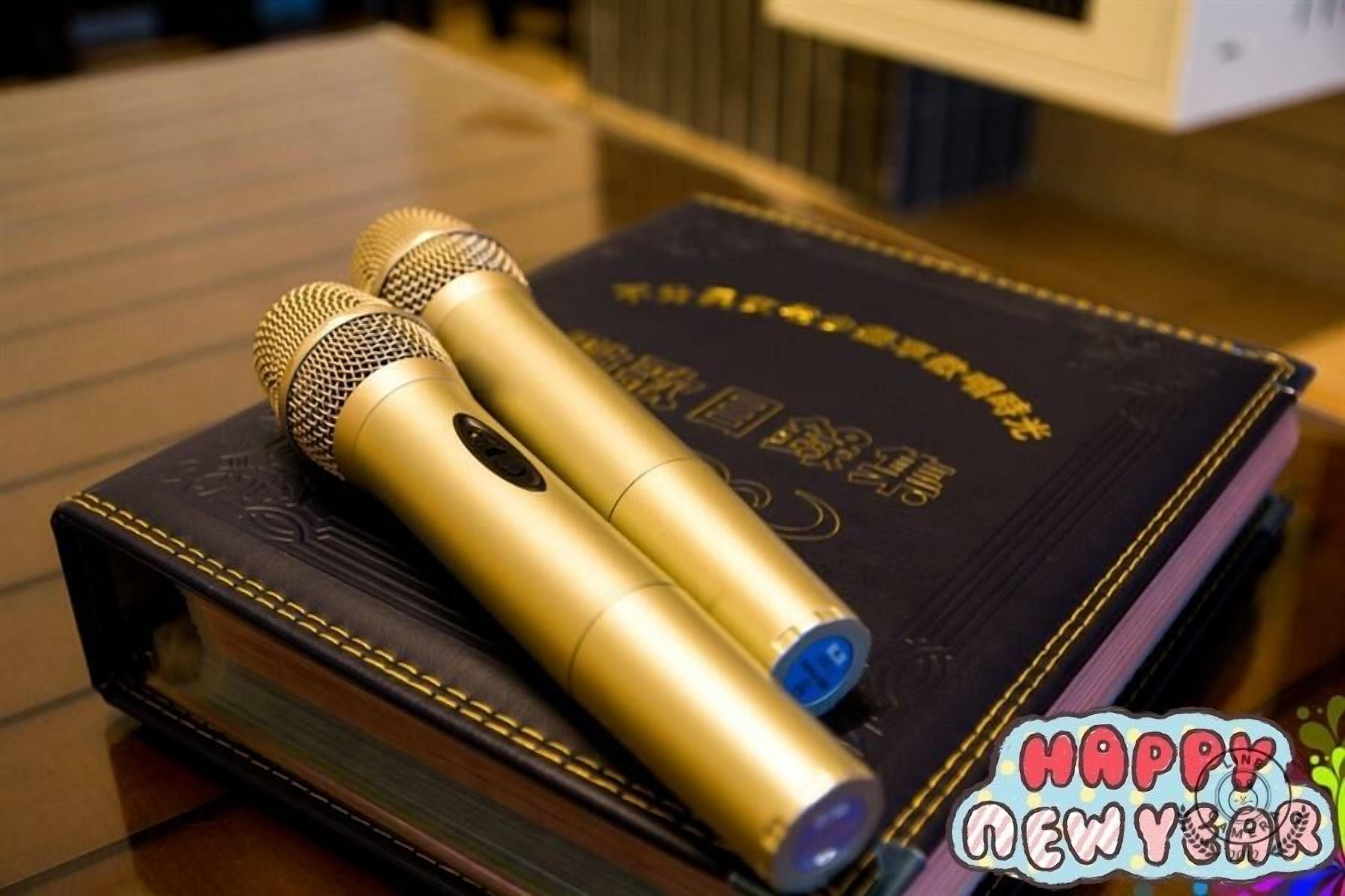 Two gold-colored microphones on a dark book with gold detailing.