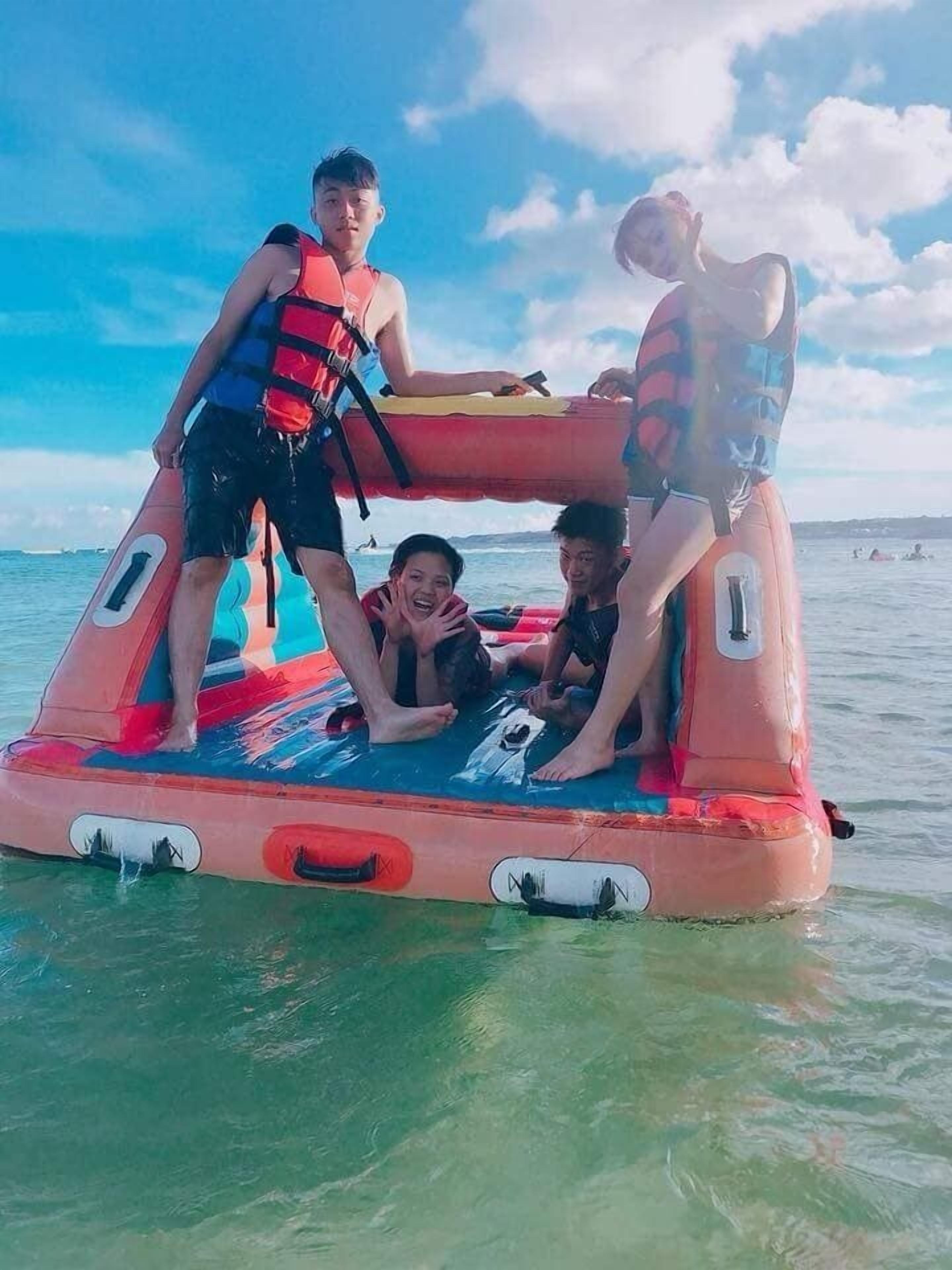 A group of people on a colorful inflatable water platform in a body of water.