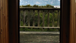 Habitación con piso de madera y vista a montañas a través de una puerta abierta.
