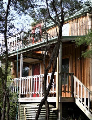 Een houten chalet met balkon, omringd door bomen.