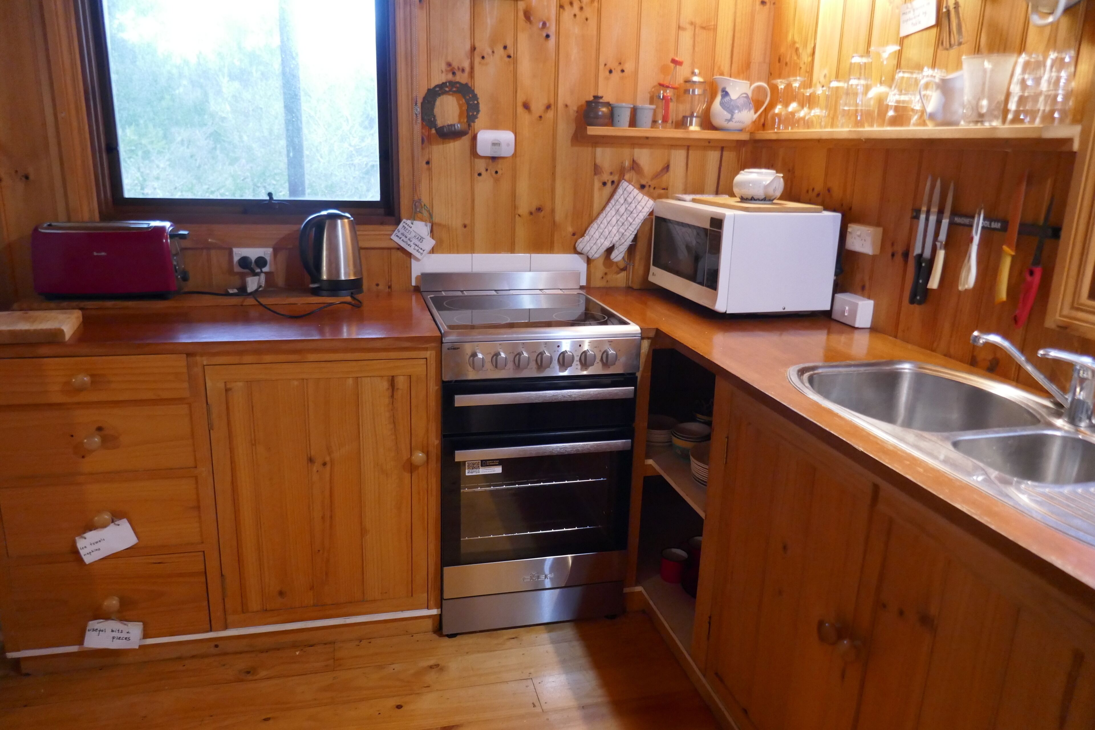 A kitchen with wooden cabinets, a stainless steel stove, a microwave, and a sink.