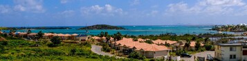 Zona residencial costera con casas, una carretera y vista al mar con barcos.