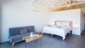 A modern room with a bed, a sofa, and a wooden table. - Villa Jwi Lavi Boutique Hotel (Cul de Sac)