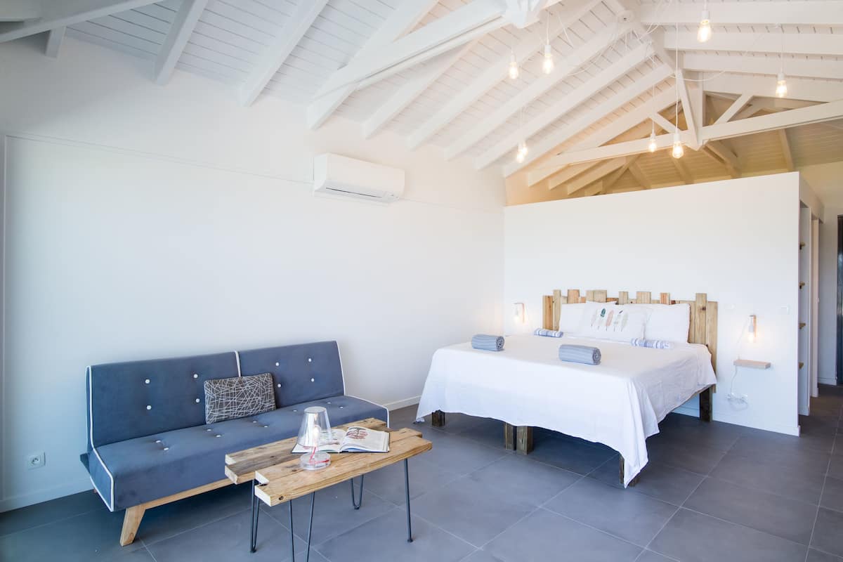 A modern room with a bed, a sofa, and a wooden table.