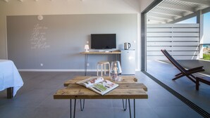 A modern room with a wooden table, a TV, and a balcony with a chair. - Villa Jwi Lavi Boutique Hotel (Cul de Sac)