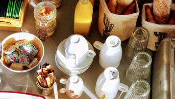 Una mesa de desayuno con diversos alimentos, como pan, mantequilla, mermelada y juegos de té.