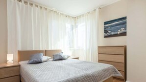 Quarto com cama, mesas de cabeceira, abajur e um quadro na parede.