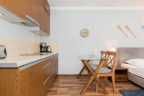 A compact kitchen with wooden cabinets, a coffee maker, and a glass table with chairs.