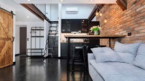 Una cocina moderna con piso de madera oscura, una escalera y una pared de ladrillo.