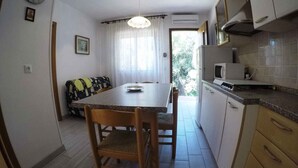 A compact kitchen with a dining area, a microwave, and a small window. - Holiday apartment mit Klimaanlage und Terrasse (Rosolina Mare)
