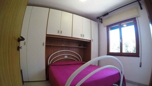 A bedroom with a bed, white wardrobe, and a window. - Holiday apartment mit Klimaanlage und Terrasse (Rosolina Mare)