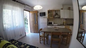 A compact living space with a kitchenette, a dining area, and a sofa. - Holiday apartment mit Klimaanlage und Terrasse (Rosolina Mare)