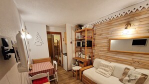 A cozy living room with a wooden sofa, a small dining table, and a kitchenette. - Charming studio for 2-3 people, 17m² south-facing in Valfréjus (Valfréjus)
