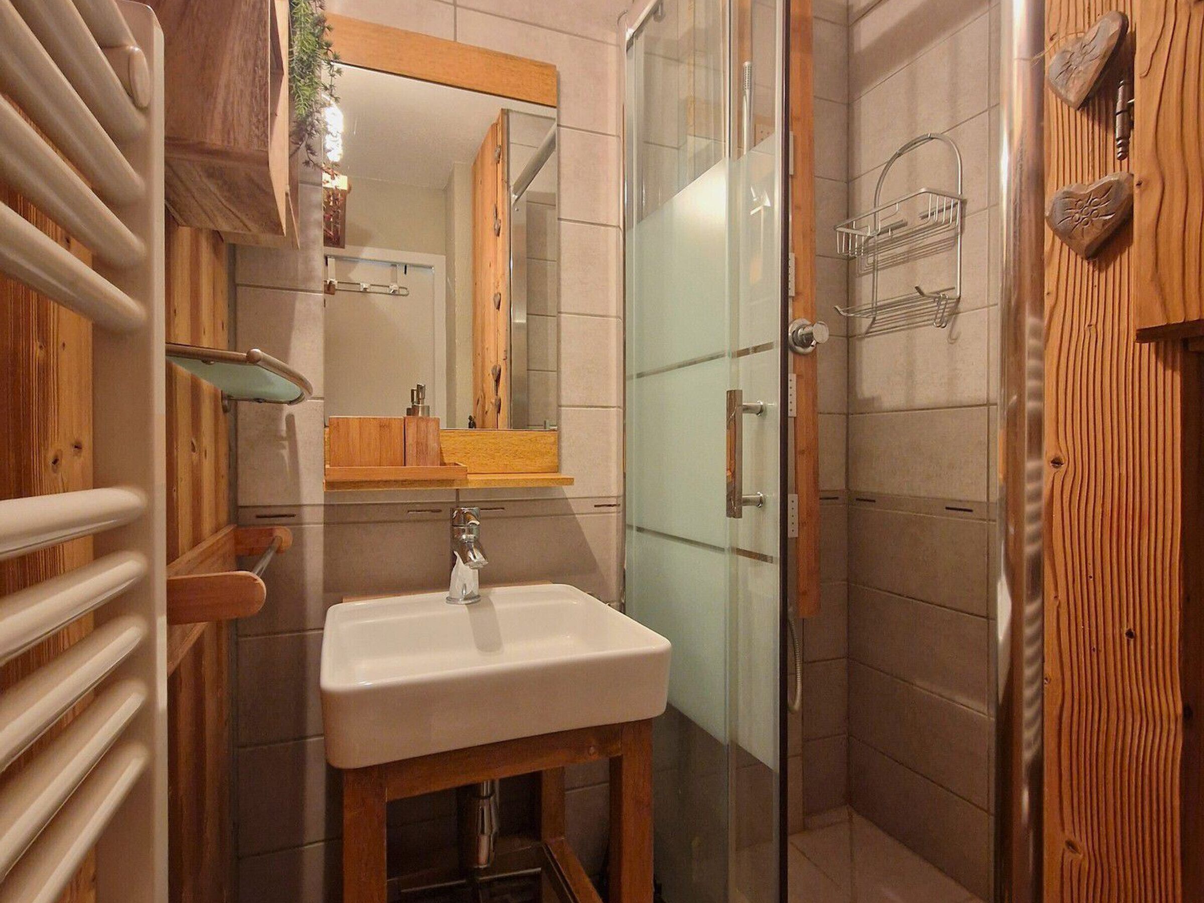 Une salle de bain avec un meuble-lavabo en bois, une cabine de douche en verre et un porte-serviettes.