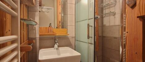 Une salle de bain avec un meuble-lavabo en bois, une cabine de douche en verre et un porte-serviettes.