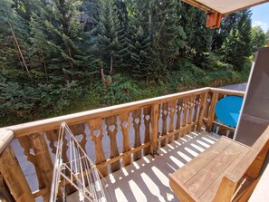 A wooden deck with a view of dense forest.