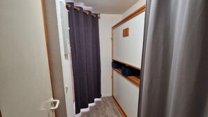 A narrow hallway with a wooden floor, a door with a white handle, and a dark curtain. - Charming Studio for 4 in Resort Center, Steps from Slopes (Valfréjus)