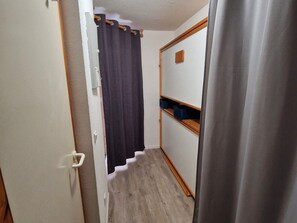 A narrow hallway with a wooden floor, a door with a white handle, and a dark curtain. - Charming Studio for 4 in Resort Center, Steps from Slopes (Valfréjus)