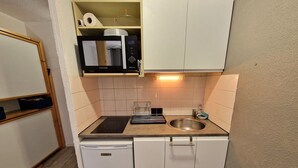 A compact kitchen with a built-in microwave, a sink, and a compact dishwasher. - Charming Studio for 4 in Resort Center, Steps from Slopes (Valfréjus)