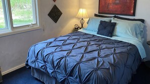 A bedroom with a large bed, a window, a wall clock, and a painting. - PICTURESQUE BLUFF SIDE APARTMENT IN HOME (Colorado Springs)