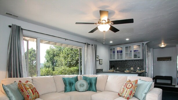 A modern living room with a sectional sofa, a glass coffee table, and a ceiling fan. - PICTURESQUE BLUFF SIDE APARTMENT IN HOME (Colorado Springs)