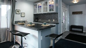 A compact kitchen with a central island, two bar stools, and a dining area. - PICTURESQUE BLUFF SIDE APARTMENT IN HOME (Colorado Springs)