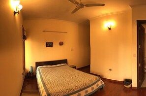 A bedroom with a bed, a ceiling fan, wall sconces, a clock, and a door. - The place to stay when you are in New Delhi (New Delhi)