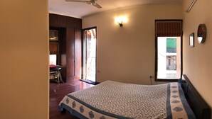 A bedroom with a bed, a ceiling fan, a wall-mounted light, a window with a view, and a door leading to another room. - The place to stay when you are in New Delhi (New Delhi)