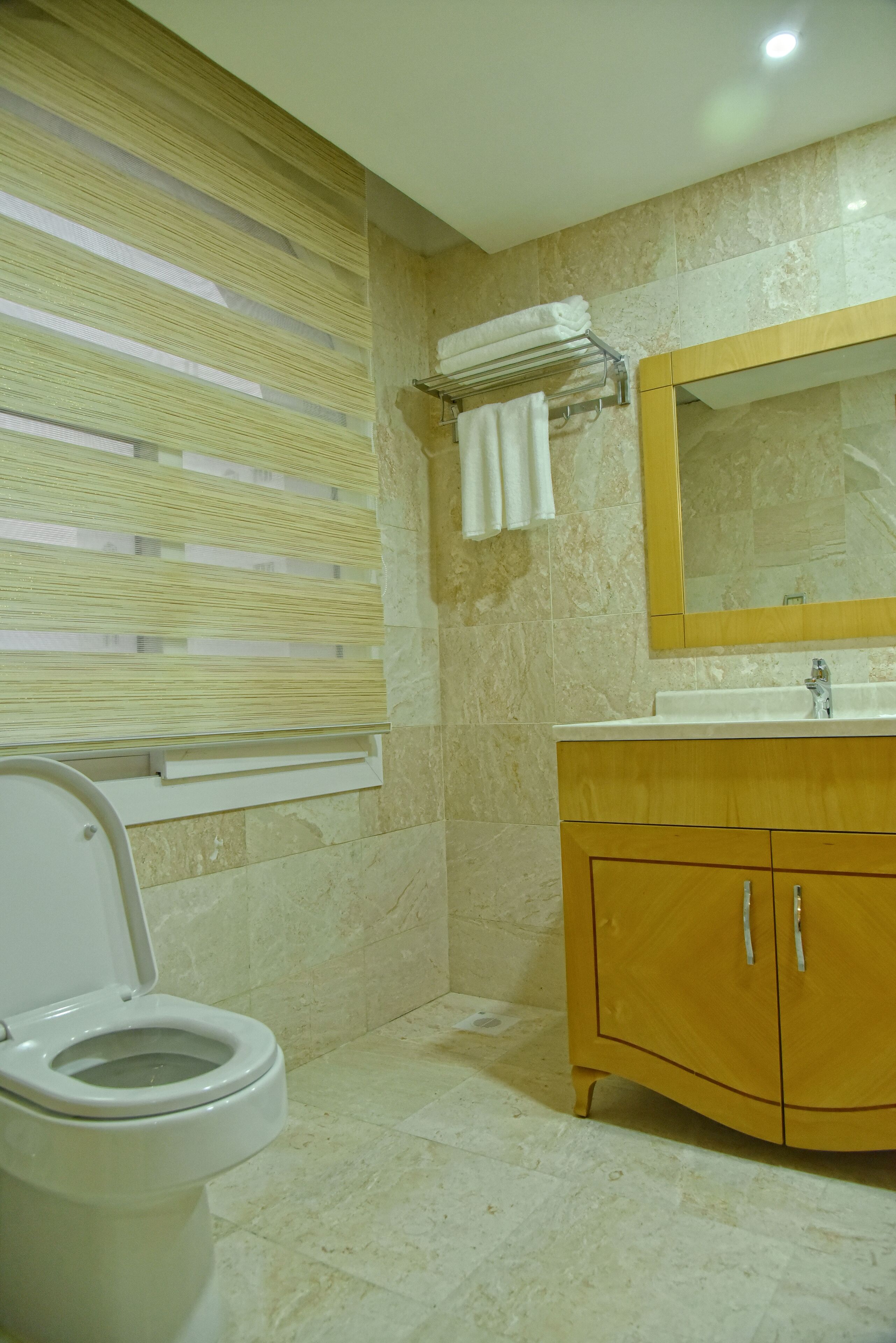 A bathroom with a toilet, a sink with a mirror, and a towel rack.
