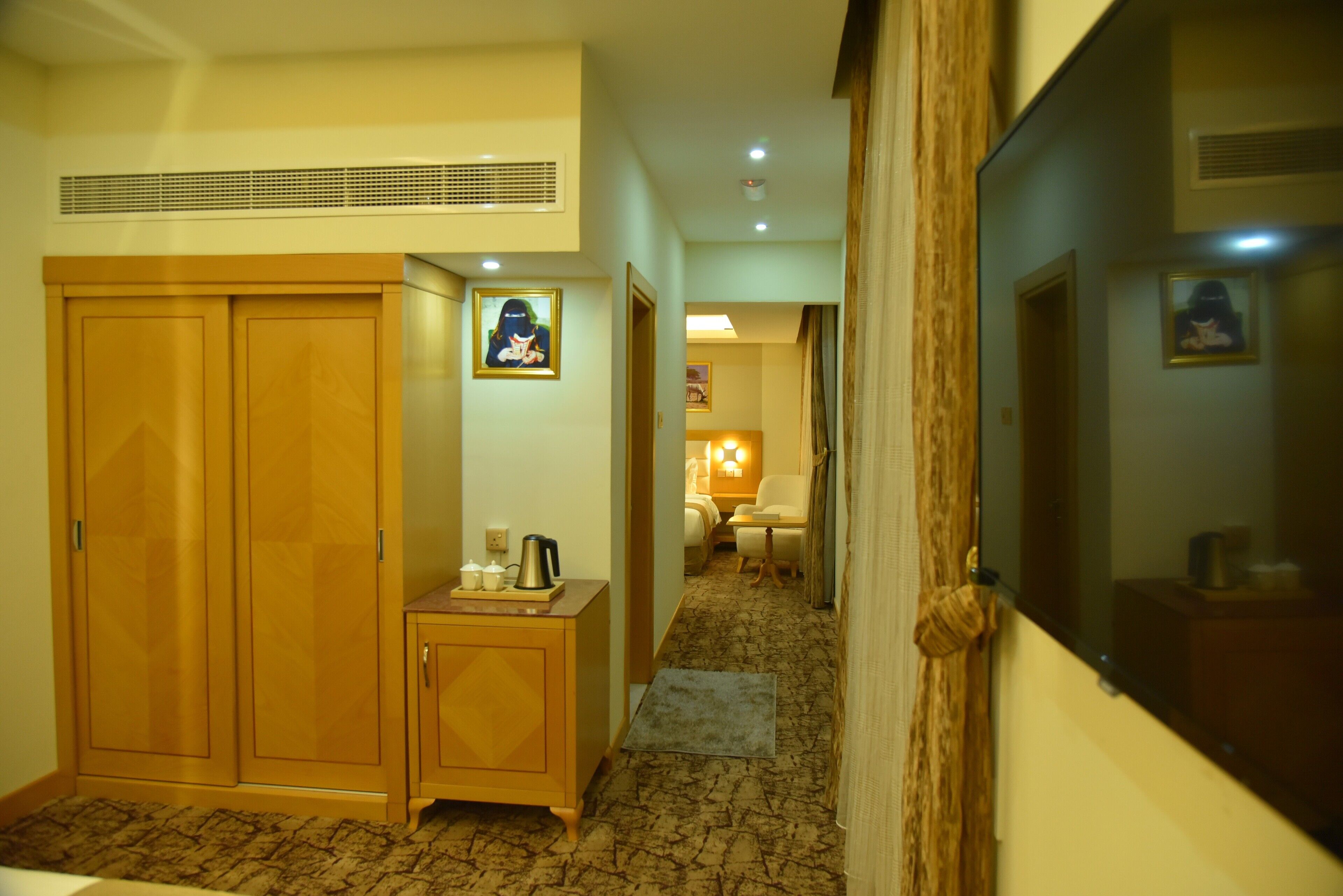 Un pasillo con armarios de madera, un mueble pequeño y un cuadro en la pared.