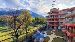Un hotel de varios pisos con balcones, un patio interior y campos escalonados al fondo.