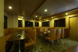 A dining area with a long table, multiple booths, and ceiling fans.