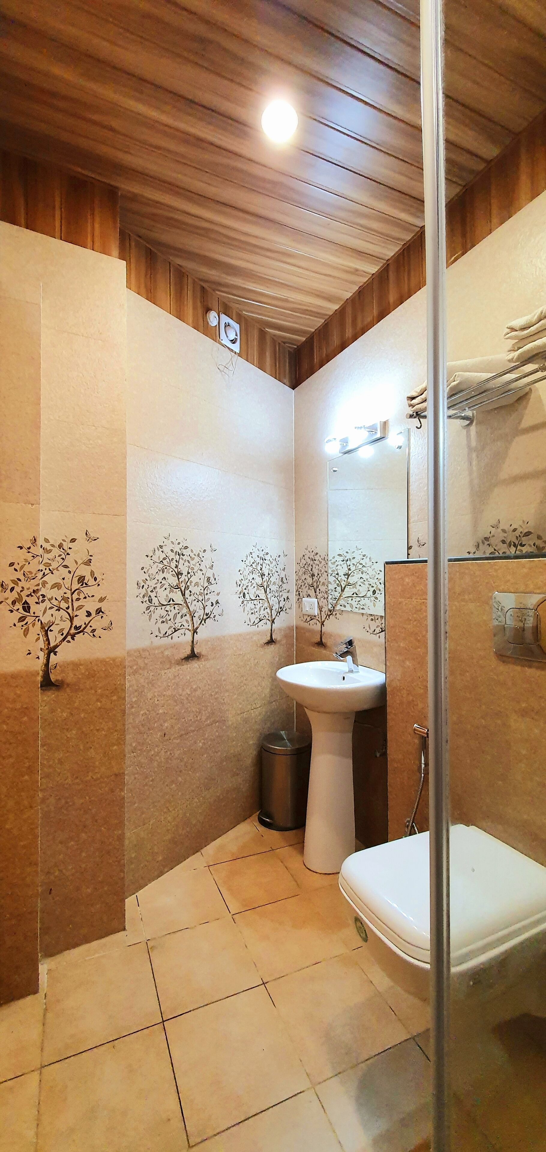 A bathroom with a wooden ceiling, a sink, a toilet, and a shower area.