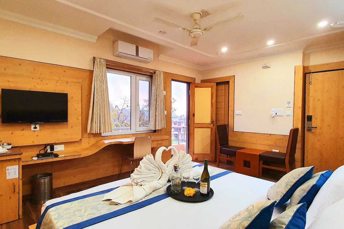 A hotel room with a bed, a TV, a desk, a window, and a door.