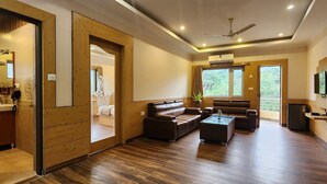 Amplia sala de estar con piso de madera, sofás de cuero, una mesa de centro y un televisor montado en la pared.
