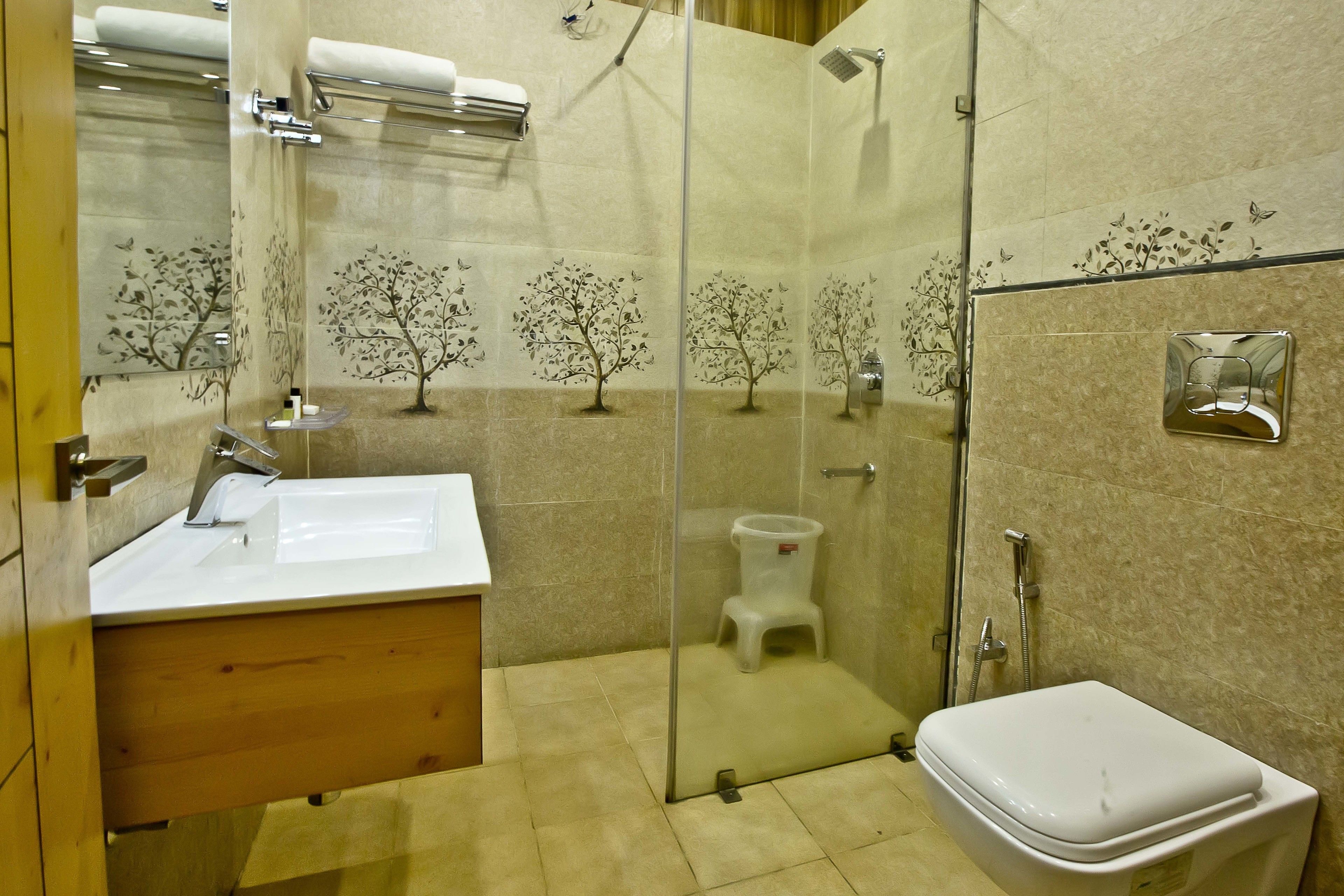Casa de banho com chuveiro de vidro, lavatório branco e sanita.