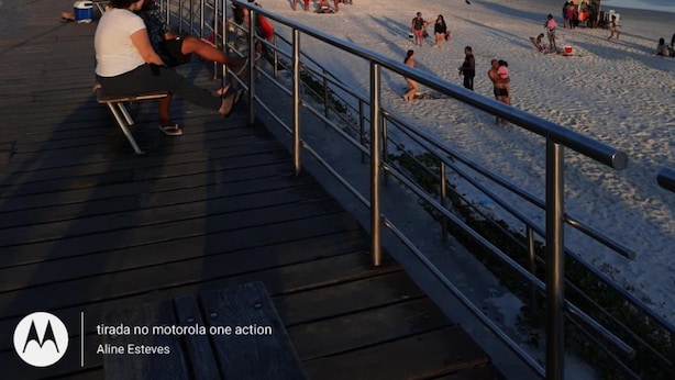 A beachside promenade with a wooden deck and metal railing, overlooking a crowded beach with people and a pizza stand. - Aloha Hostel Cabo Frio (Cabo Frio)