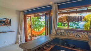 A kitchen with a view of greenery, a hammock, and a tiled backsplash. - Villa Giulia Morro (Cairu)
