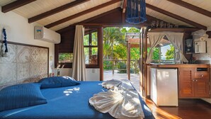 A bedroom with a bed, a window, a kitchenette, and a view of the outdoors. - Villa Giulia Morro (Cairu)