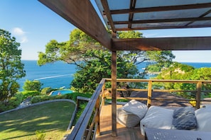A wooden deck with a view of the sea, a pool, and lush greenery. - Villa Giulia Morro (Cairu)