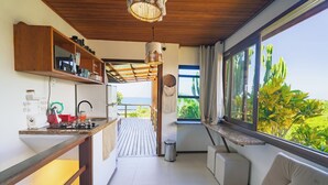 A modern kitchen with a wooden ceiling, a dining area with a view, and a seating area with a window overlooking greenery. - Villa Giulia Morro (Cairu)