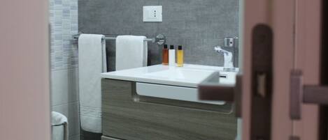 A modern bathroom with a white sink, grey tiles, and a towel rack.