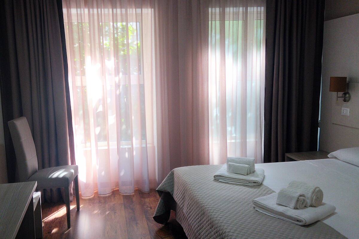 Une chambre d’hôtel avec un lit, une chaise, un bureau et un téléviseur.