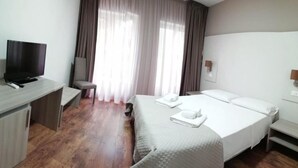 Une chambre d’hôtel avec un lit, un bureau avec une télévision et une chaise.