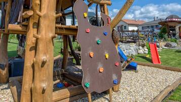Une structure d’escalade en bois, dotée de différentes prises de couleurs variées et d’un toboggan.