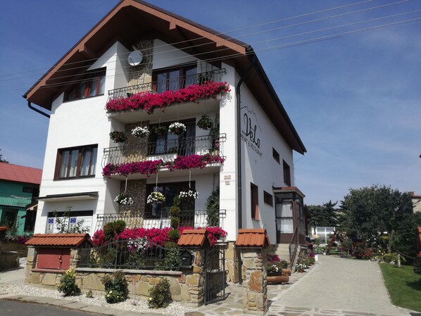 A two-story building with balconies adorned with flowers, a stone facade, and a sign indicating it is a private and restaurant. - VeLa (Malý Slavkov)