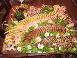 A large platter of sliced meats and vegetables, garnished with flowers and herbs. - VeLa (Malý Slavkov)