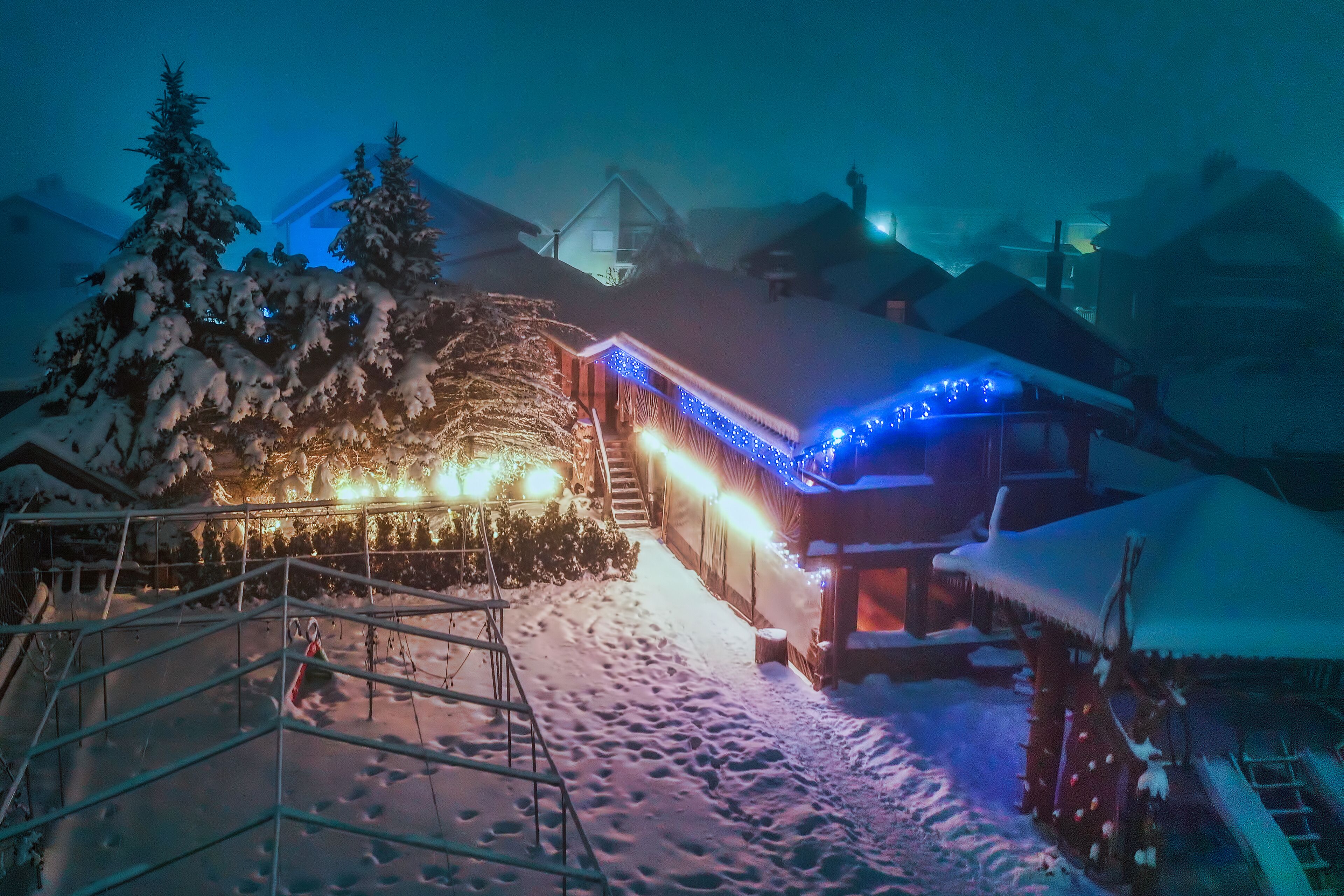 Zona exterior cubierta de nieve con una estructura de madera, posiblemente una cabaña, y una escalera que lleva a ella.