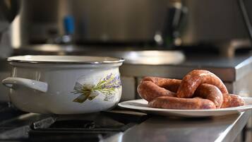Una cocina con una olla de esmalte blanco y un plato de salchichas sobre la encimera.